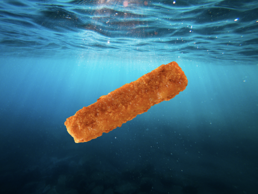Ein paniertes Fischstäbchen schwimmt unter Wasser im Meer